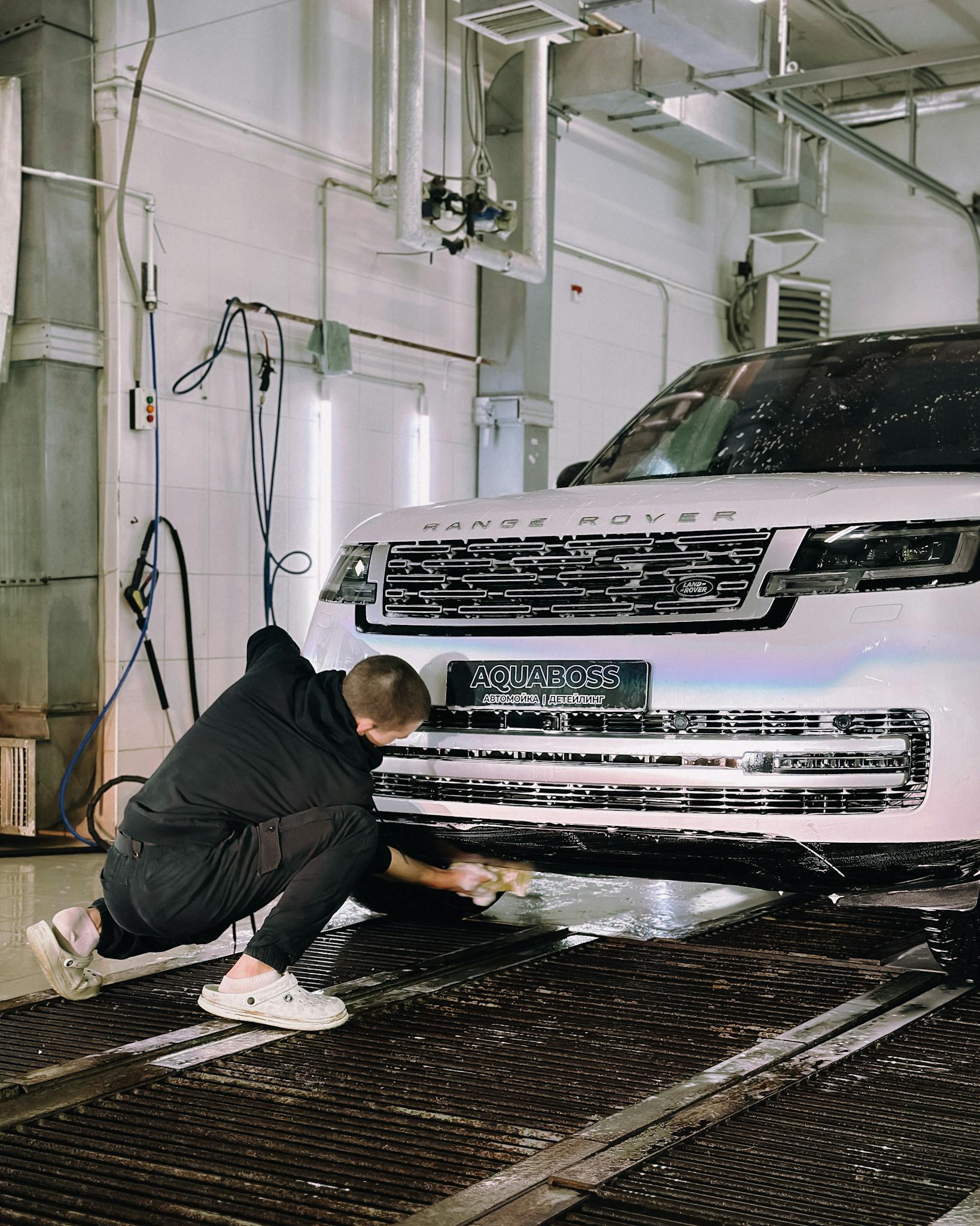 A worker cleaning a Range Rover in an indoor car wash with attention to detail.